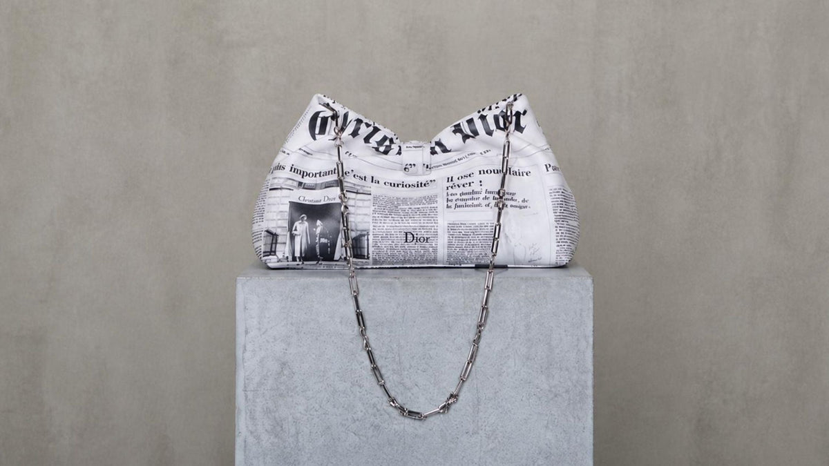 Dior newspaper print slouchy chain-strap bag from Jonathan Anderson's Cruise 2027 collection, as seen at Phoenix Style.