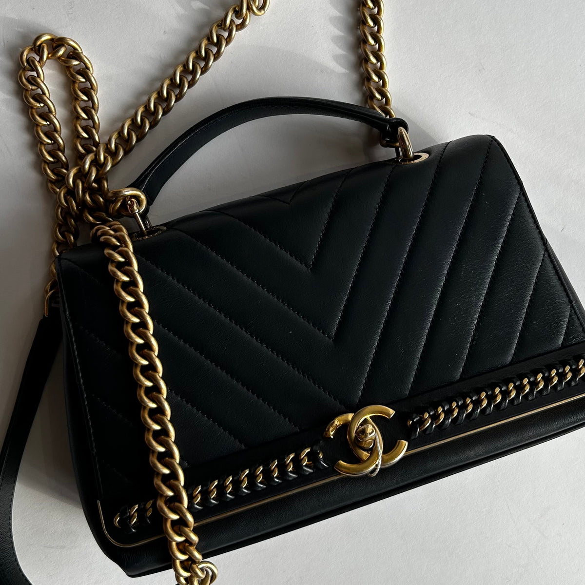 Close up of Navy Preloved Chanel Handbag with Gold chain on white background.