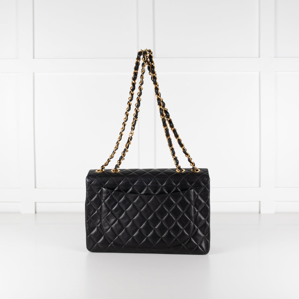 Preloved Back of Black Chanel Vintage 34 Maxi Lambskin Single Flap bag on white background. Cobham Surrey.