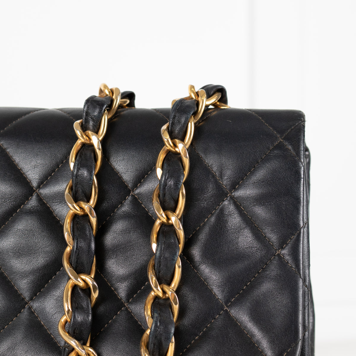 Close up of gold hardware chain and black leather. 