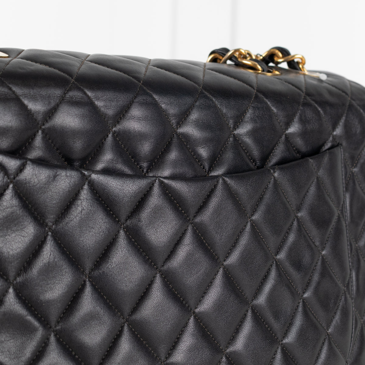 Close up of Black Chanel Vintage 34 Maxi Lambskin Single Flap bag on white background.