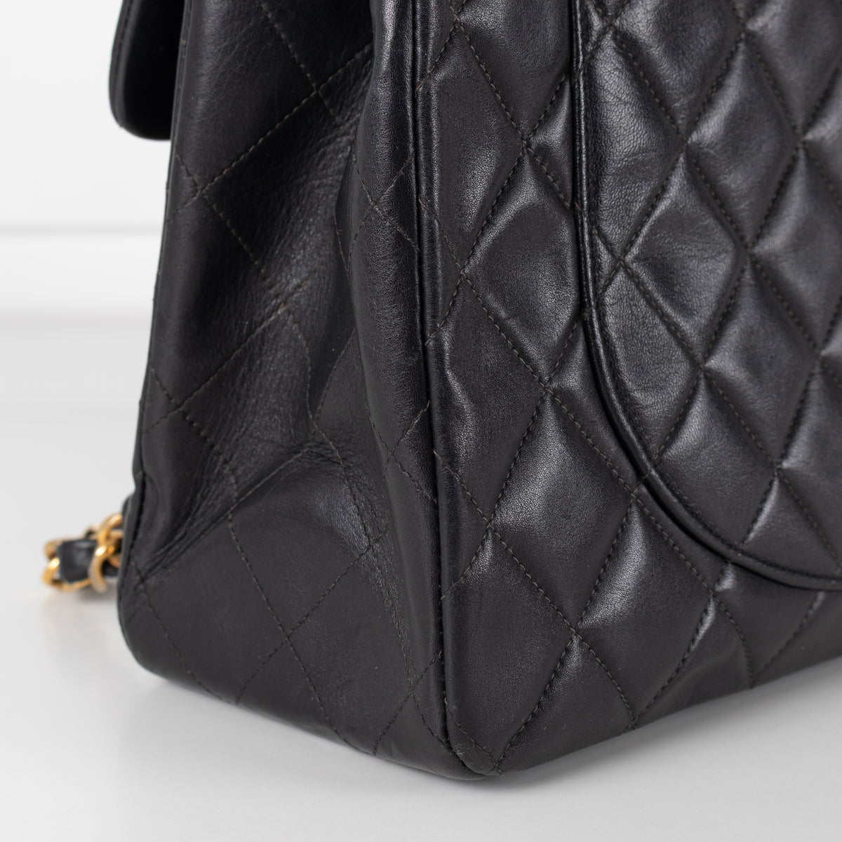 Close up of Black Chanel Vintage 34 Maxi Lambskin Single Flap bag on white background.