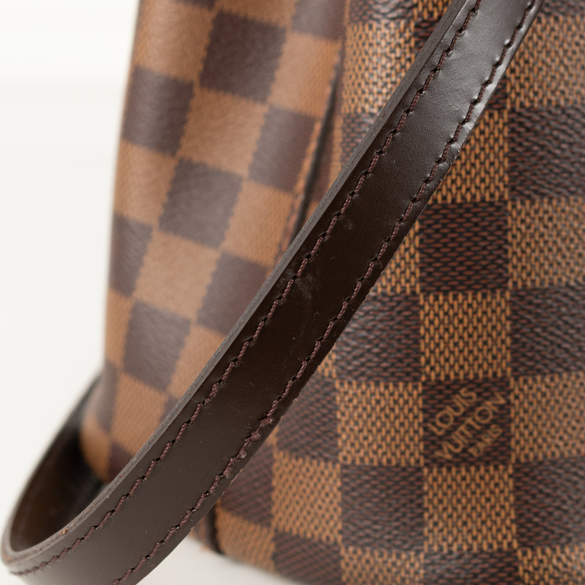 Close up of brown leather strap Louis Vuitton Damier Kensington Tote bag. 