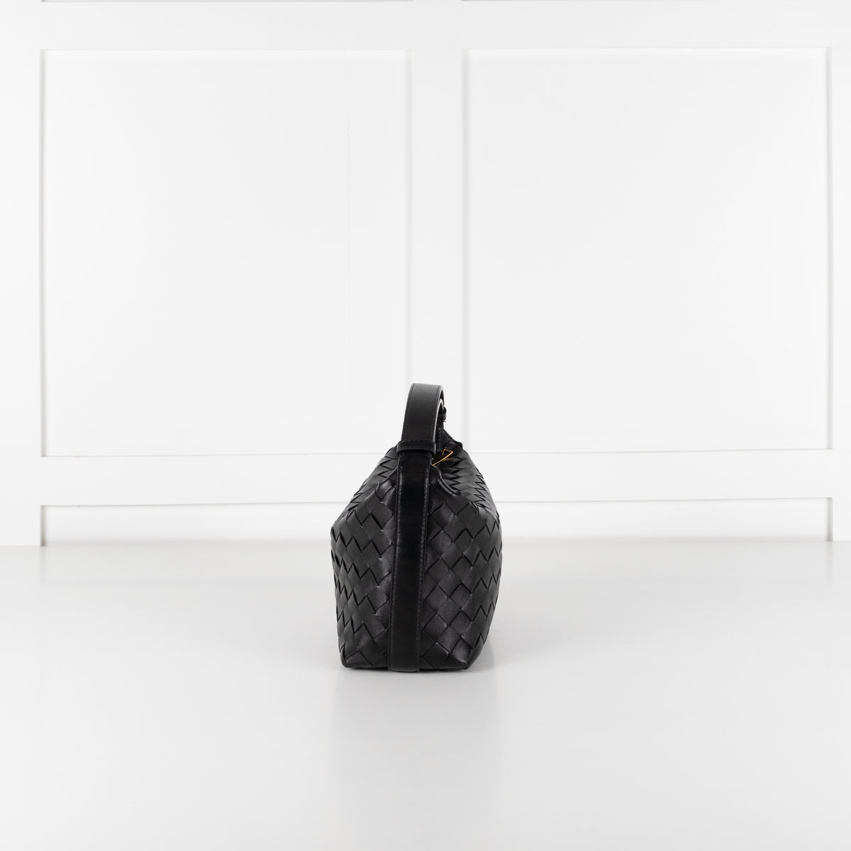 Side profile of Bottega Veneta mini Wallace bag in black intrecciato leather on white background.