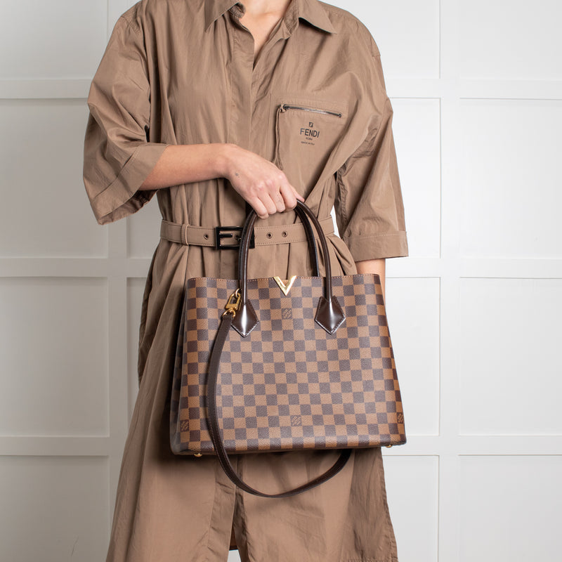 Model holding on short straps Louis Vuitton Damier Kensington Tote bag. 