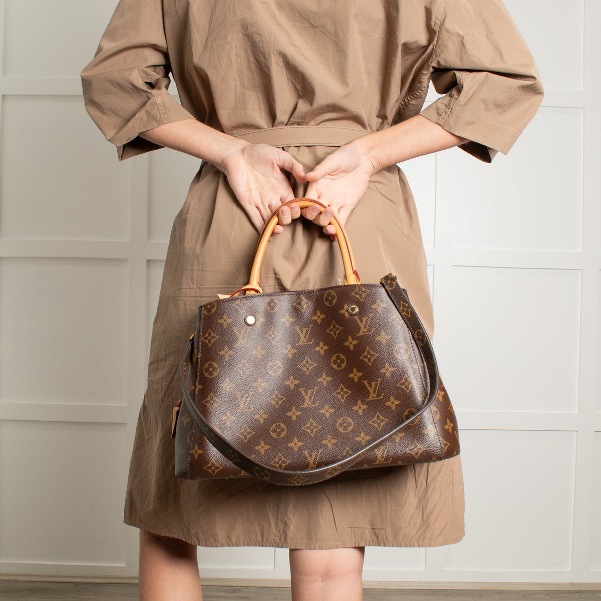 Model holding Louis Vuitton Monogram Canvas Montaigne MM on short strap with white background.