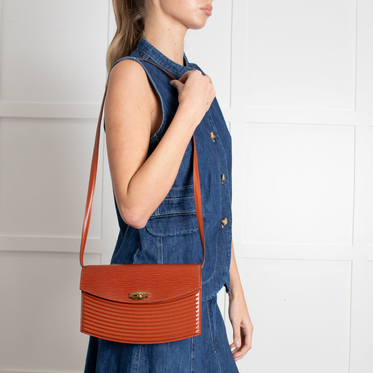 Woman wearing a denim dress with an Louis Vuitton Vintage Epi Prebourg Leather Kenya Brown 36 handbag on a white background in Phoenix Style shop.