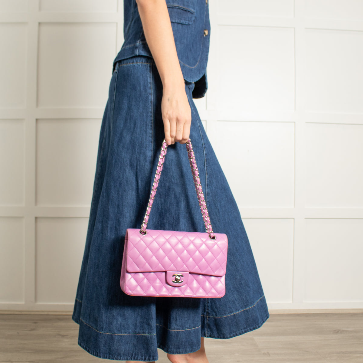 Model holding Chanel Pink Matelasse 25 Lambskin Double Flap Bag on short straps with white background.
