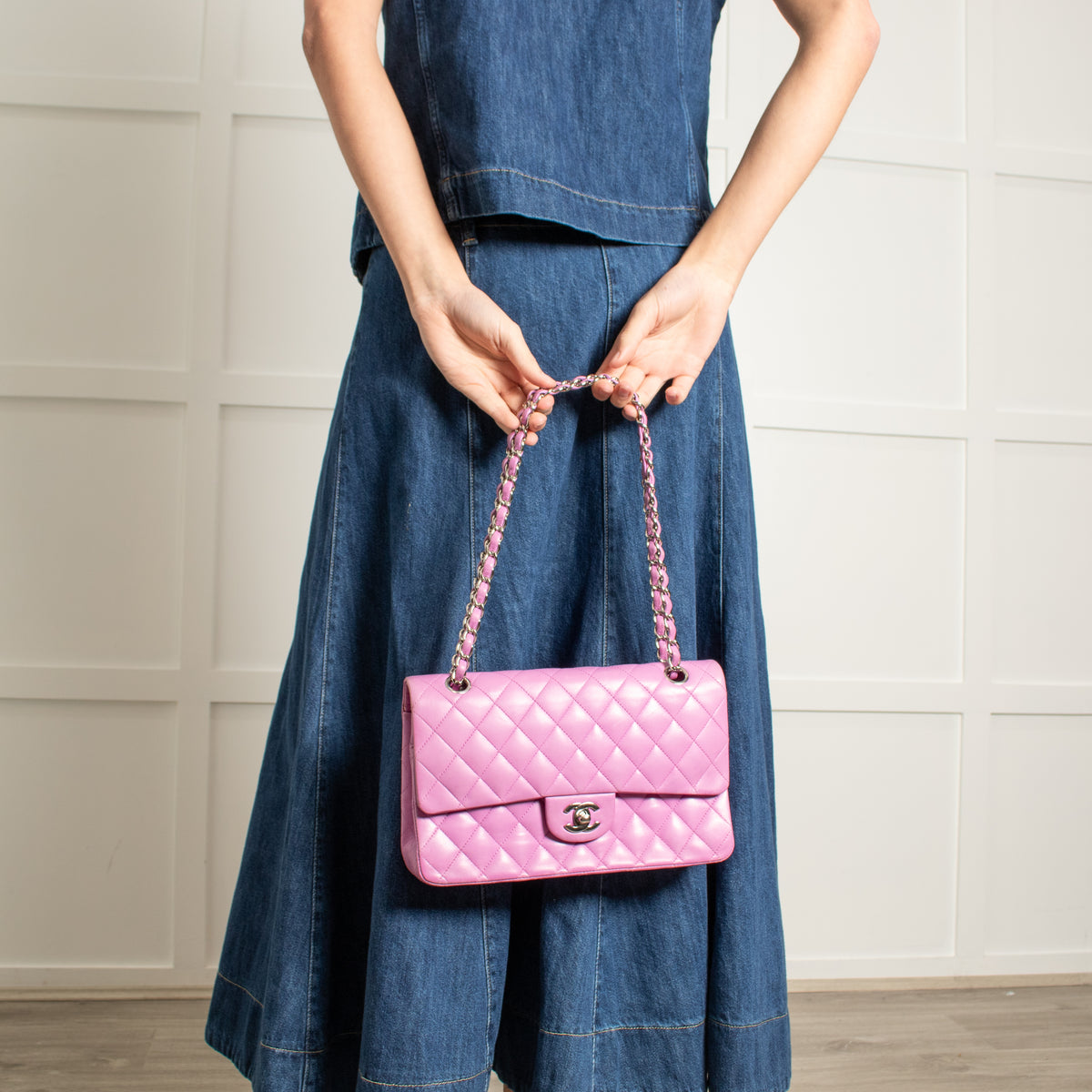 Model holding Chanel Pink Matelasse 25 Lambskin Double Flap Bag with white background on short straps.
