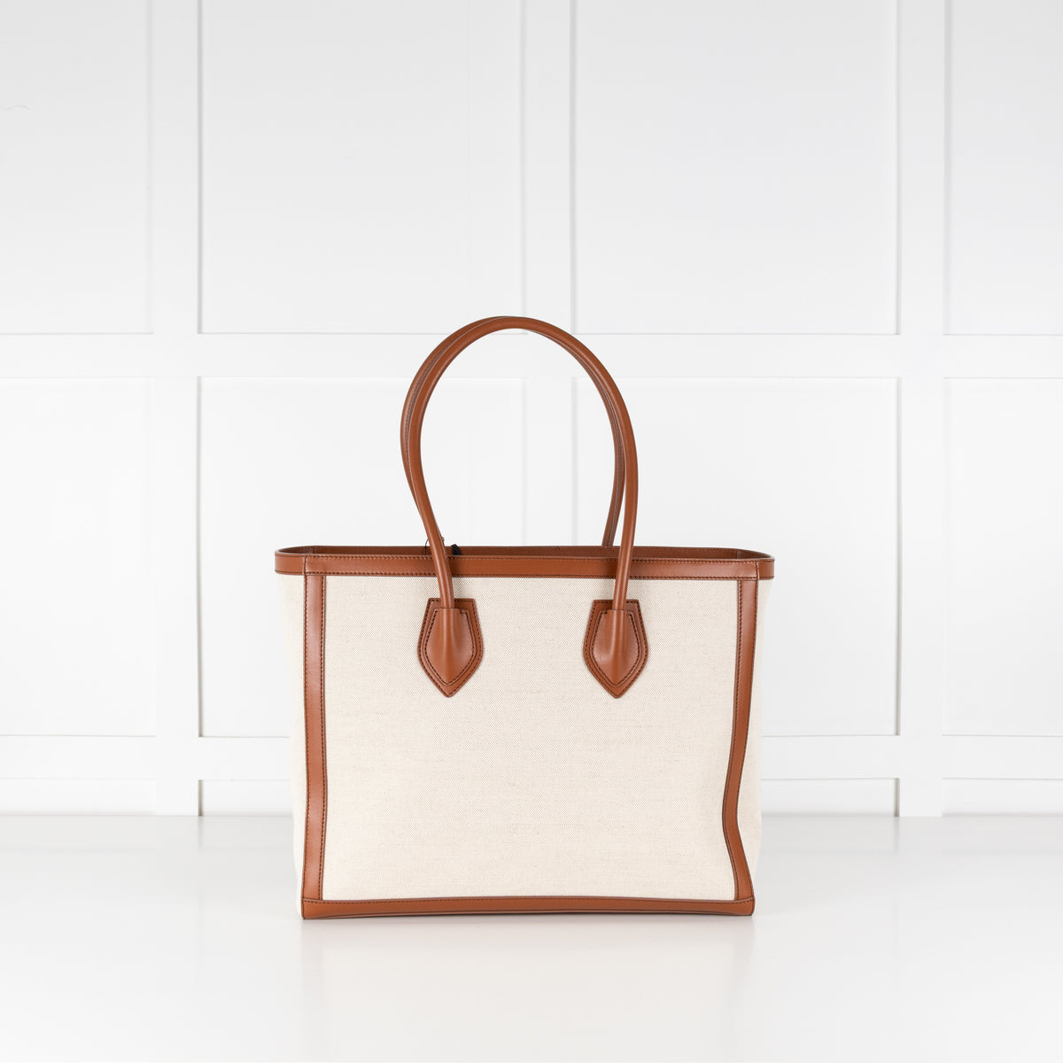 White tote bag with brown leather handles and accents on a white background