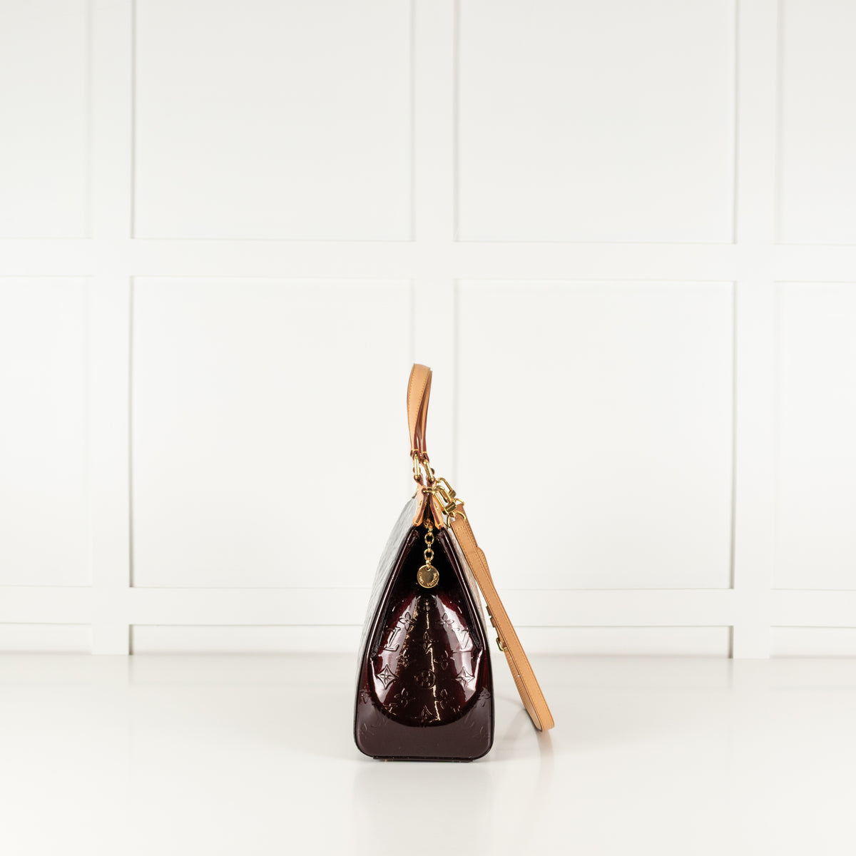 Side profile of a Louis Vuitton brown leather handbag with gold and tan straps.