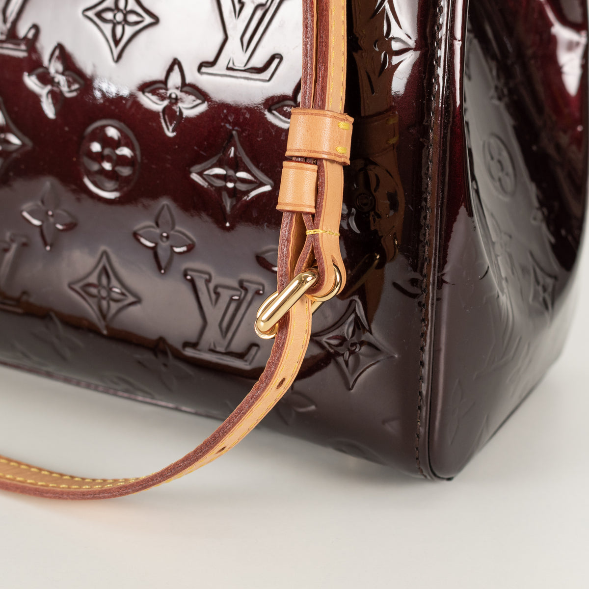 Close-up of a brown Louis Vuitton handbag on a light background. 