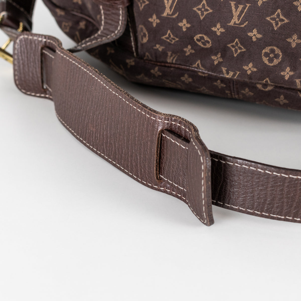 Brown leather strap of a Louis Vuitton bag on a white background