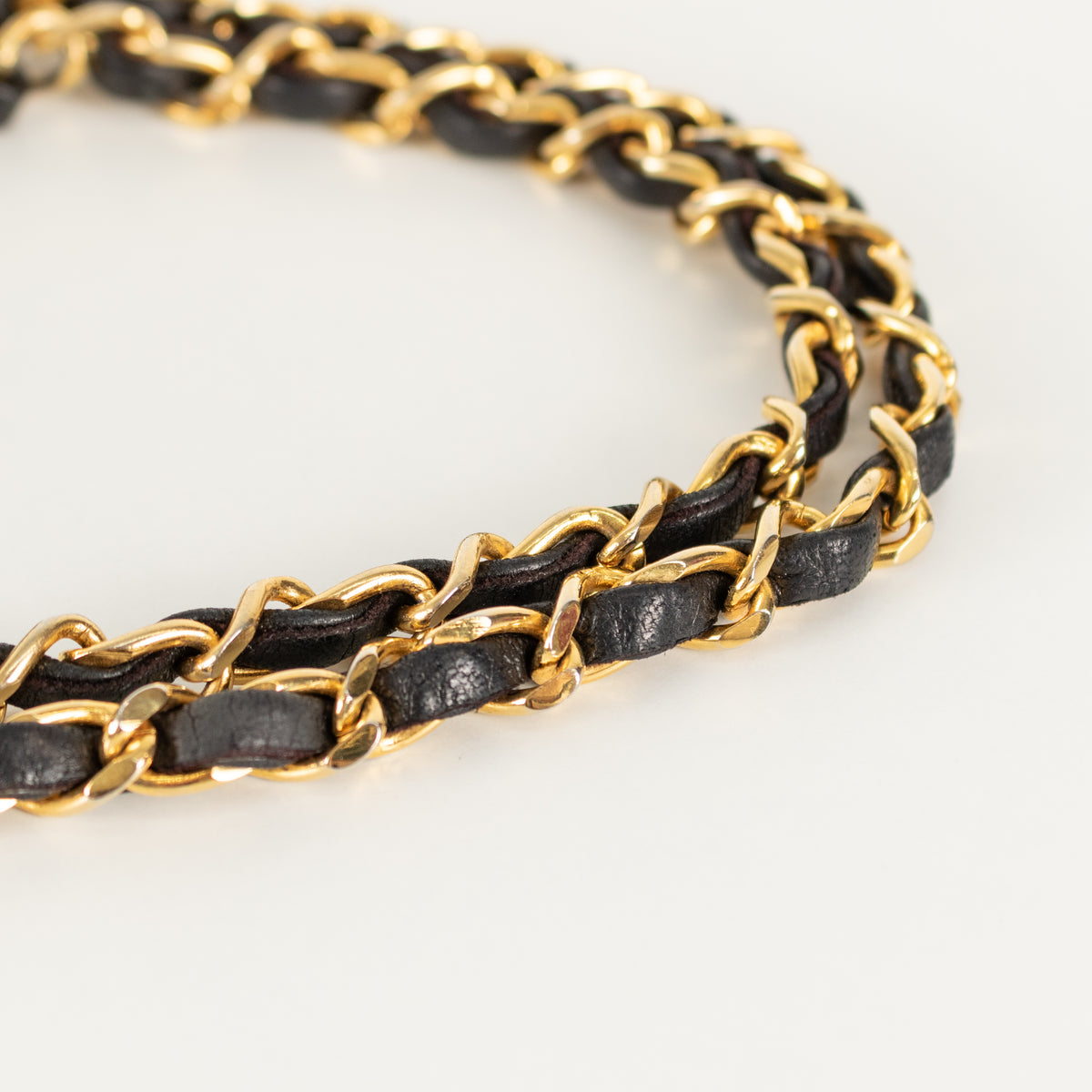 Black and gold braided Chanel handbag chain strap on a white background