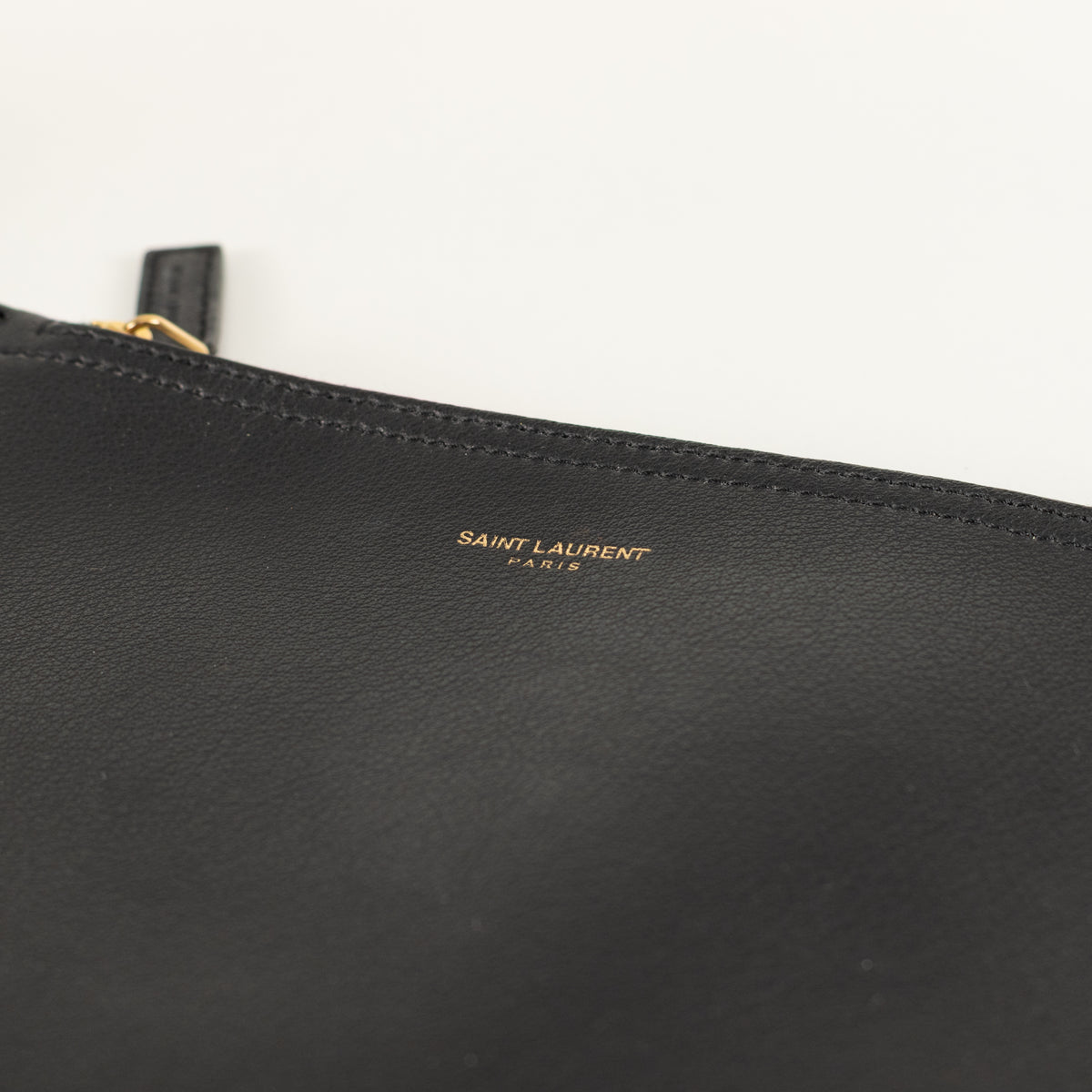 Black leather clutch bag with 'Saint Laurent' logo on a white background