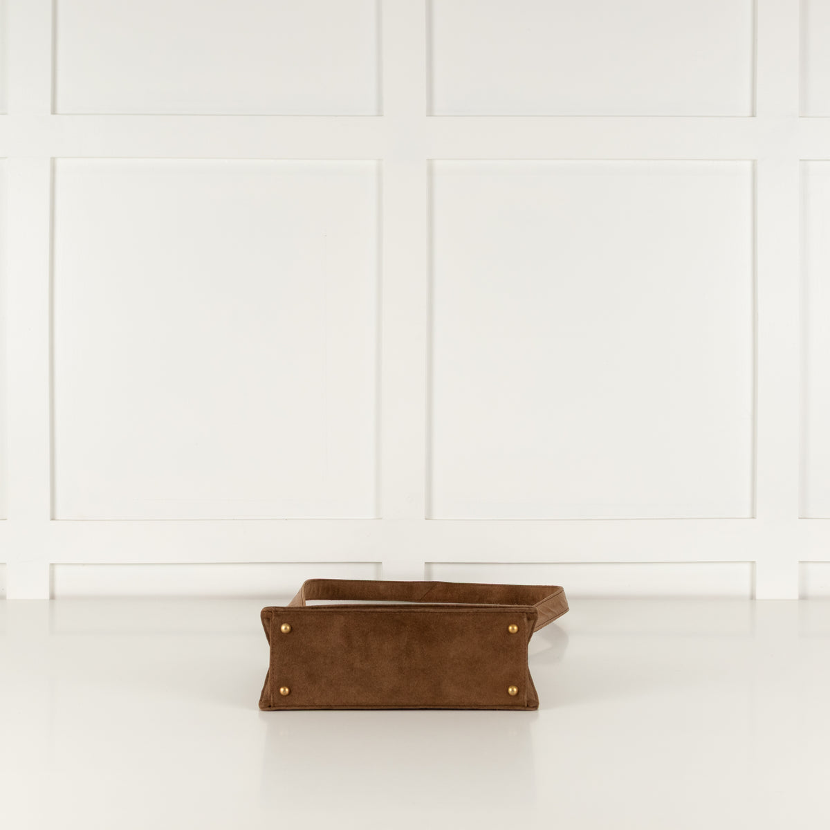 Brown leather wallet on a white surface with a white paneled wall background