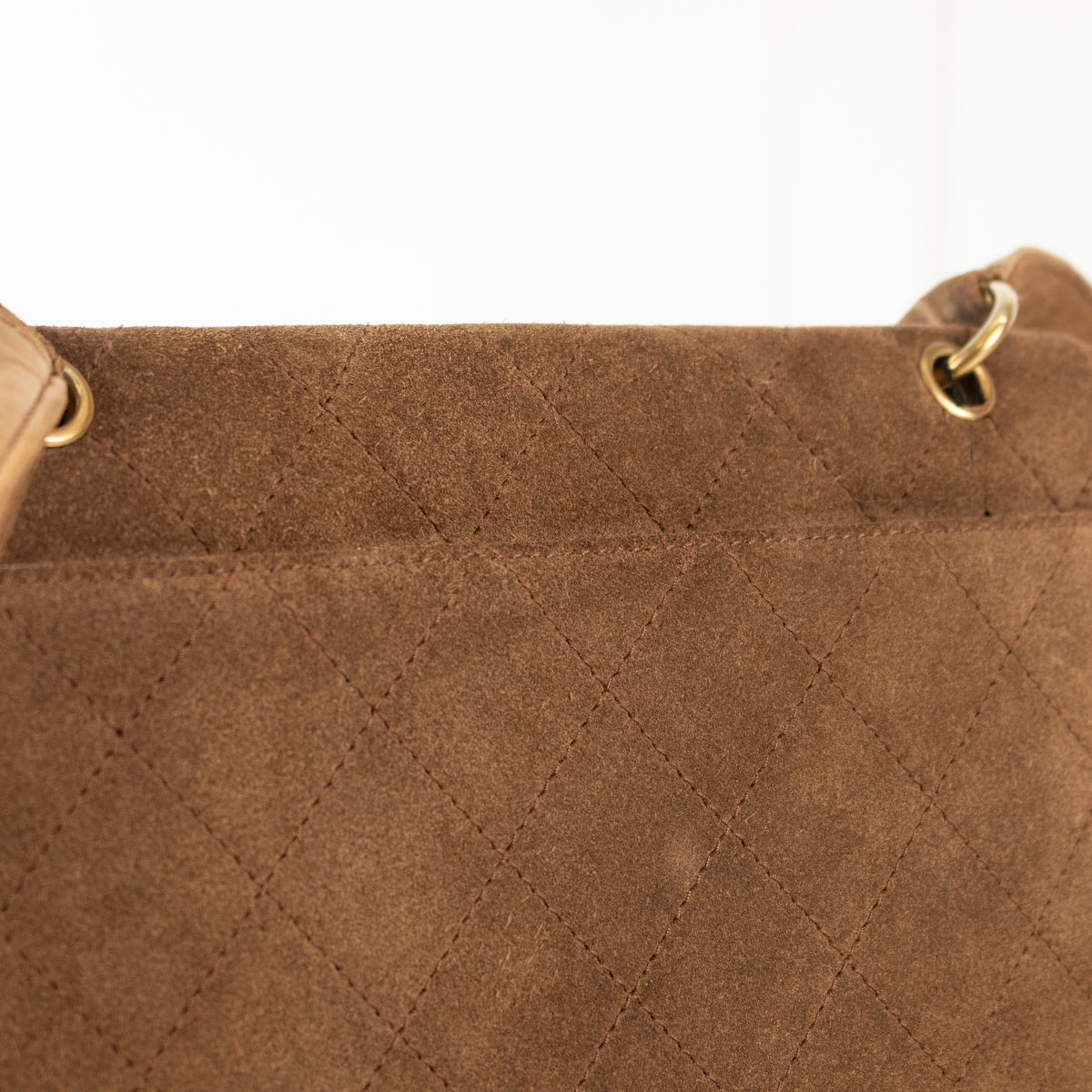 Close-up of a pre loved Chanel Brown Suede Quilted Flap Bag.