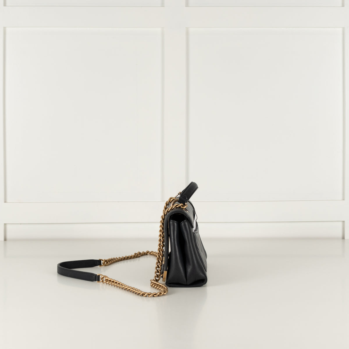 Side profile of Navy Preloved Chanel Handbag with gold chain on white background.