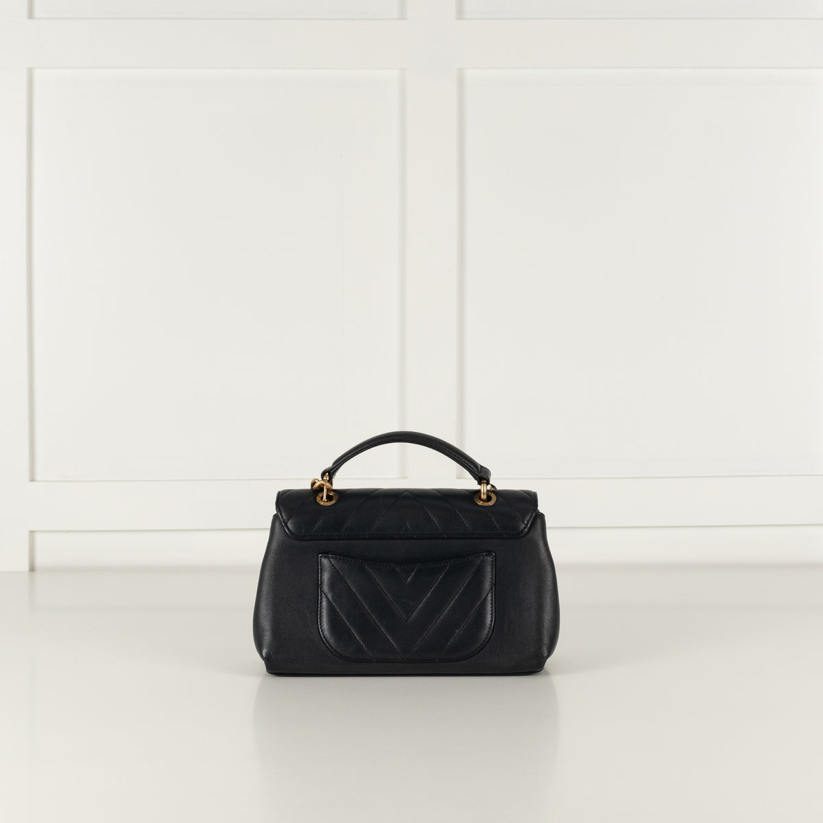 Back of Navy Preloved Chanel Handbag  with top handle and back open pocket on white background.