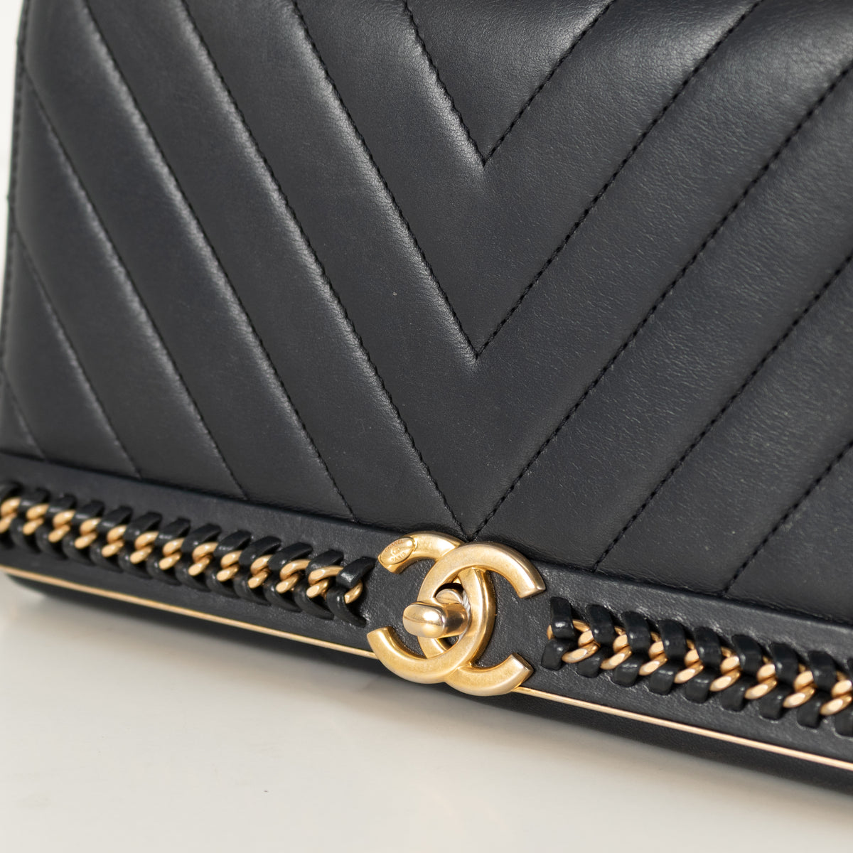 Close up of Gold CC Emblem Navy Preloved Chanel Handbag on white background.
