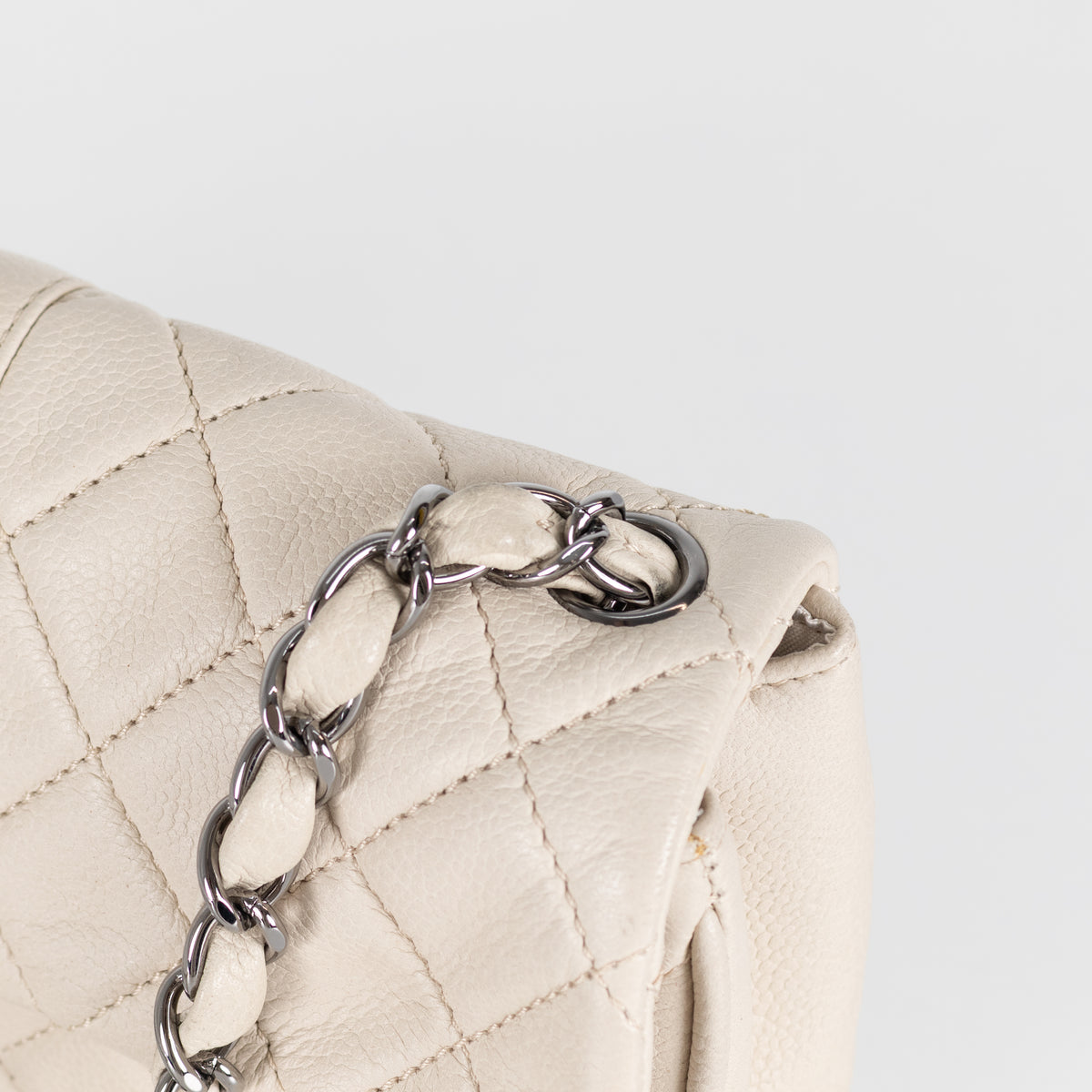 Close up of silver hardware on Preloved Chanel vintage Mademoiselle flap handbag with white background in phoenix style shop.