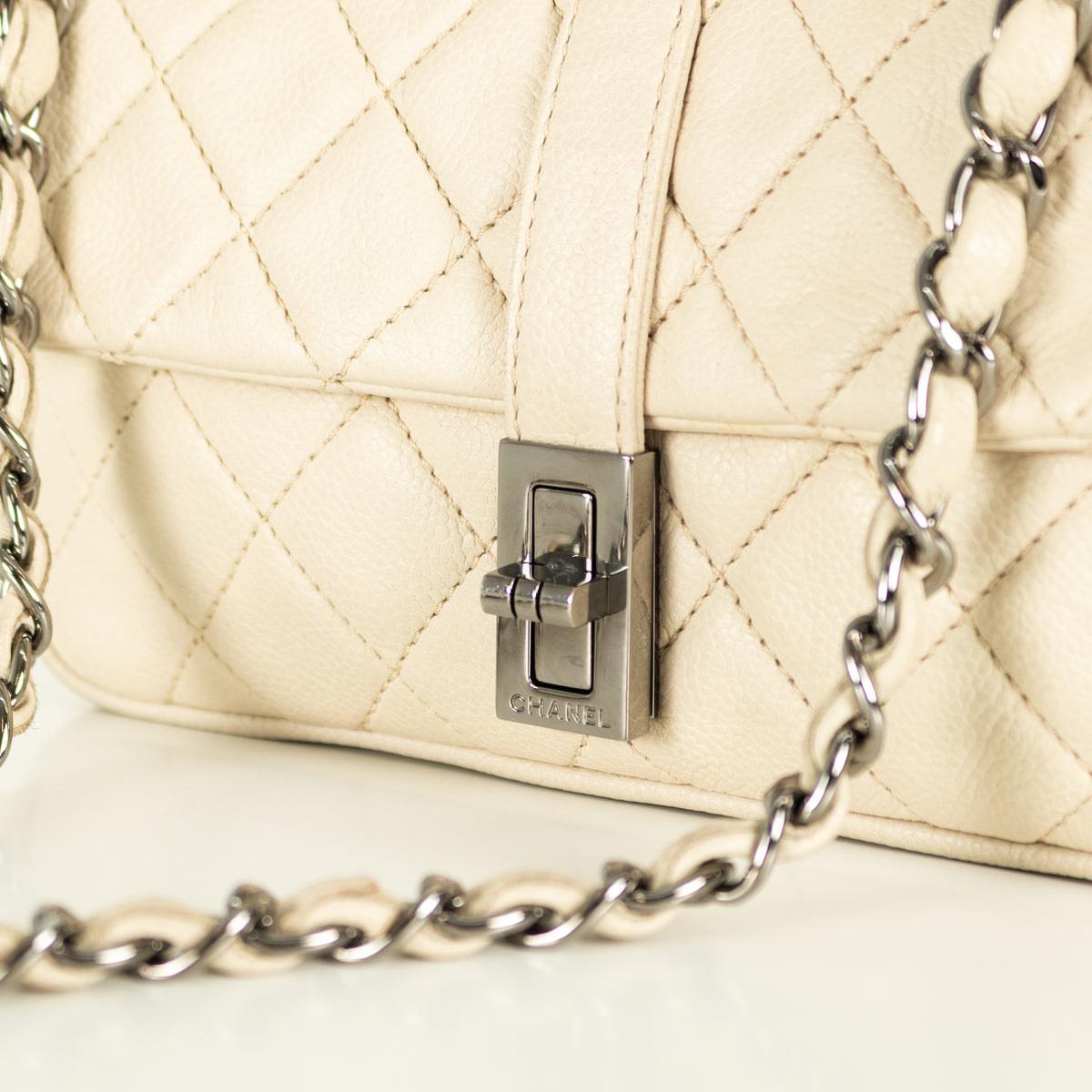 Close up of silver hardware clasp of Preloved Chanel vintage Mademoiselle flap handbag with white background in phoenix style shop.