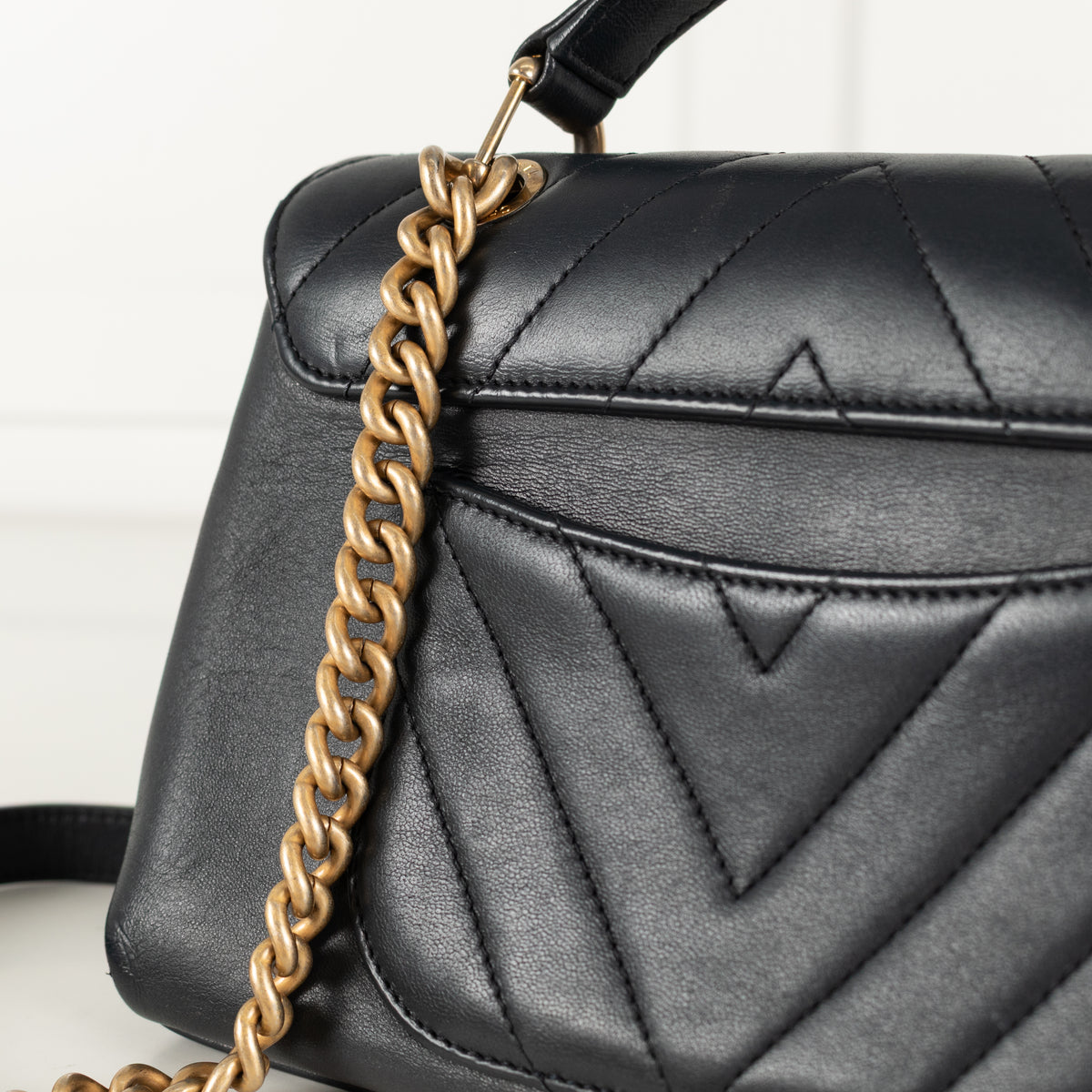 Close up of Gold hardware Navy Preloved Chanel Handbag on white background.