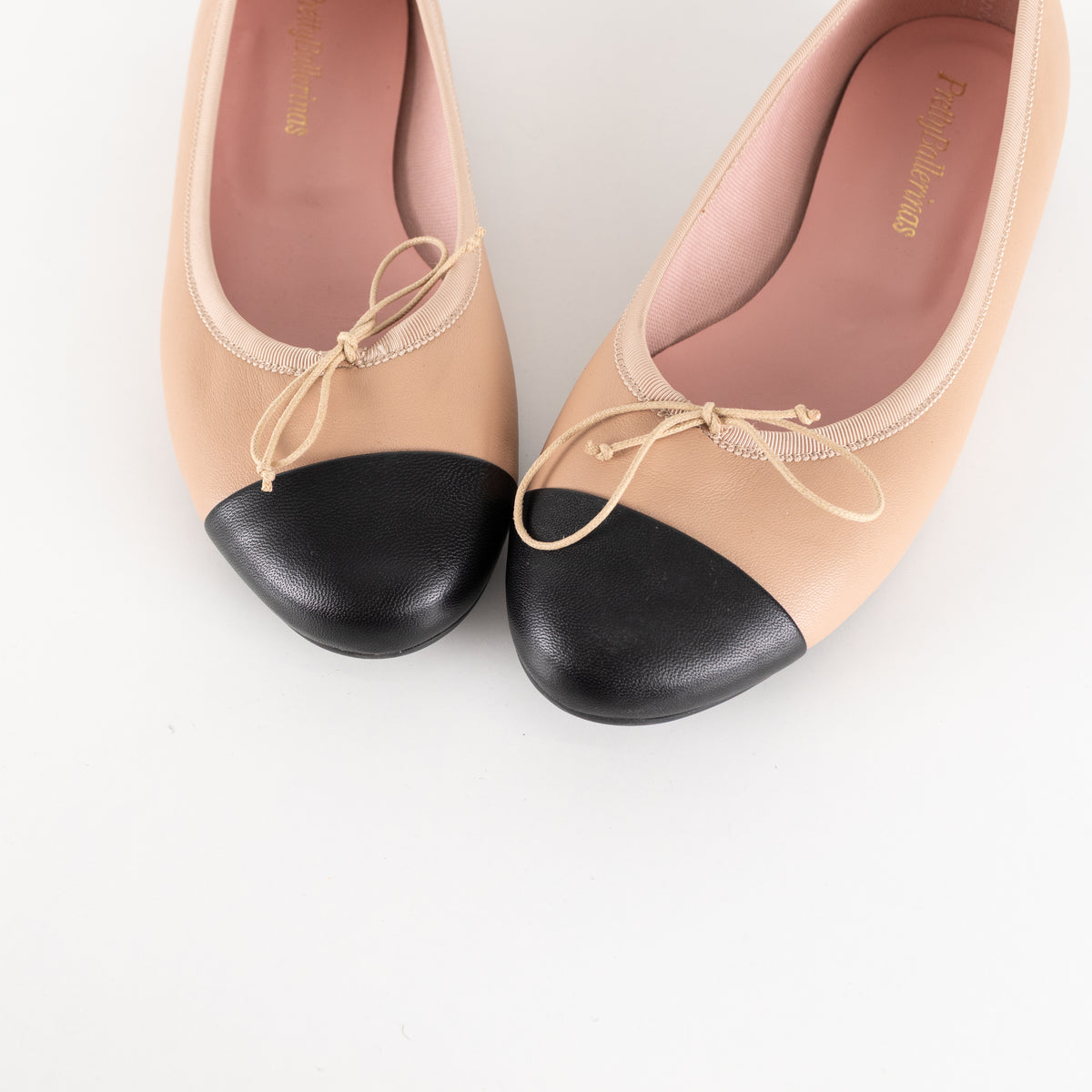 Pretty Ballerinas Nude Ballet Flats With Black Cap-Toe And Bow Detail