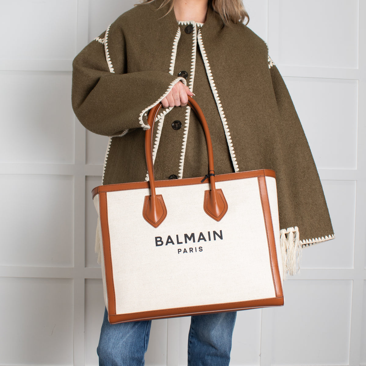 Person holding a Balmain bag against a white background