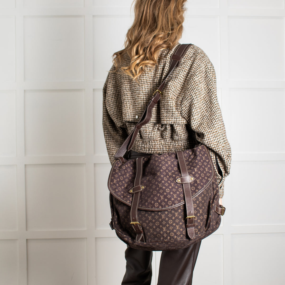 Person wearing Louis Vuitton Brown Monogram Mini Lin Saumur XL Shoulder Bag with white background.