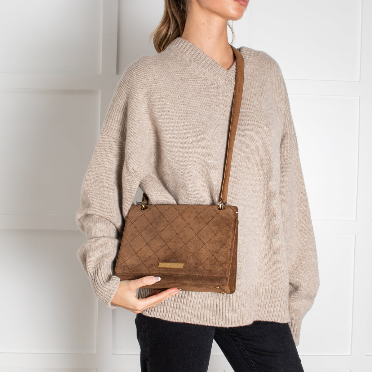 Person wearing a Chanel brown quilted flap handbag against a white background in Phoenix Style shop.