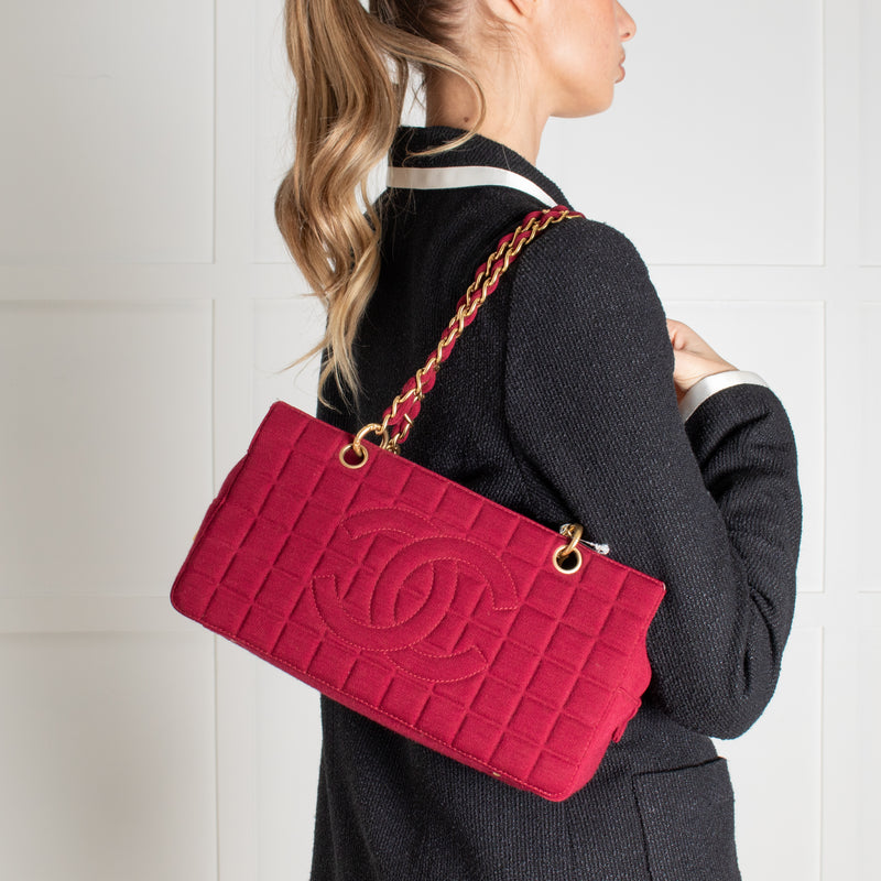 Model wearing a preloved Chanel Berry Red Jersey Chocolate Bar Chain Shoulder Bag on a white background.